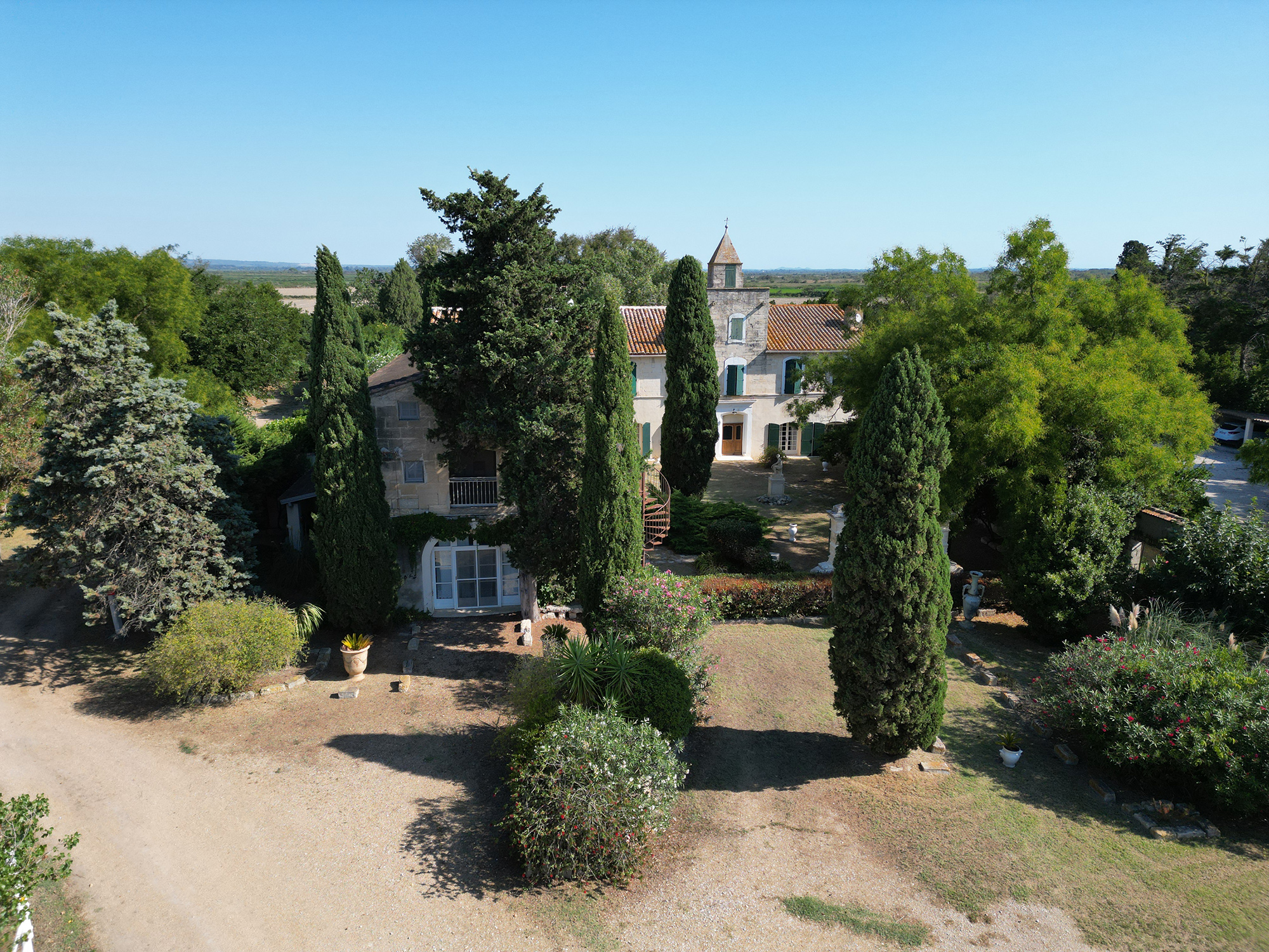 Vue aérienne du Mas du Juge entouré de cyprès et jardins en pleine campagne camarguaise